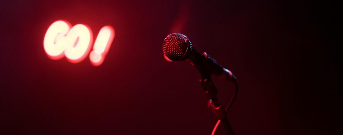 Lone Mic in a dark room with only a GO! red neon sign. 