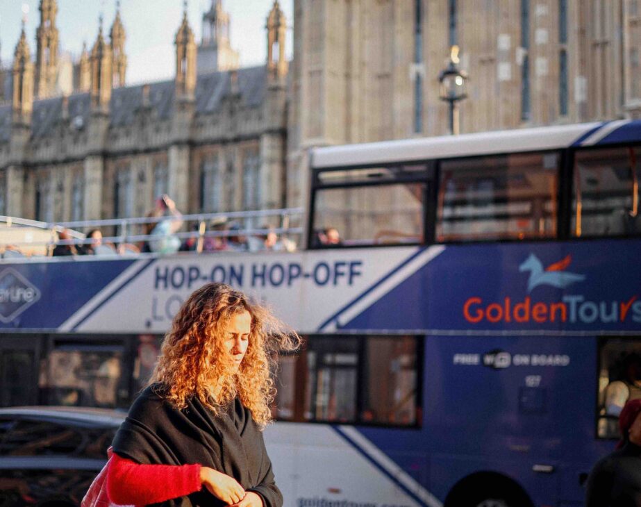 A lady in front of a hop-on hop-off bus by Westminster Abby. 